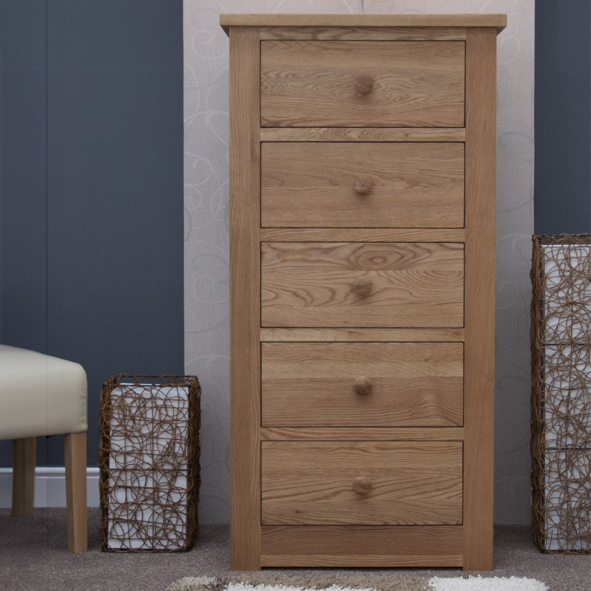 Oak chest of drawers with five drawers in bedroom setting on carpeted floor