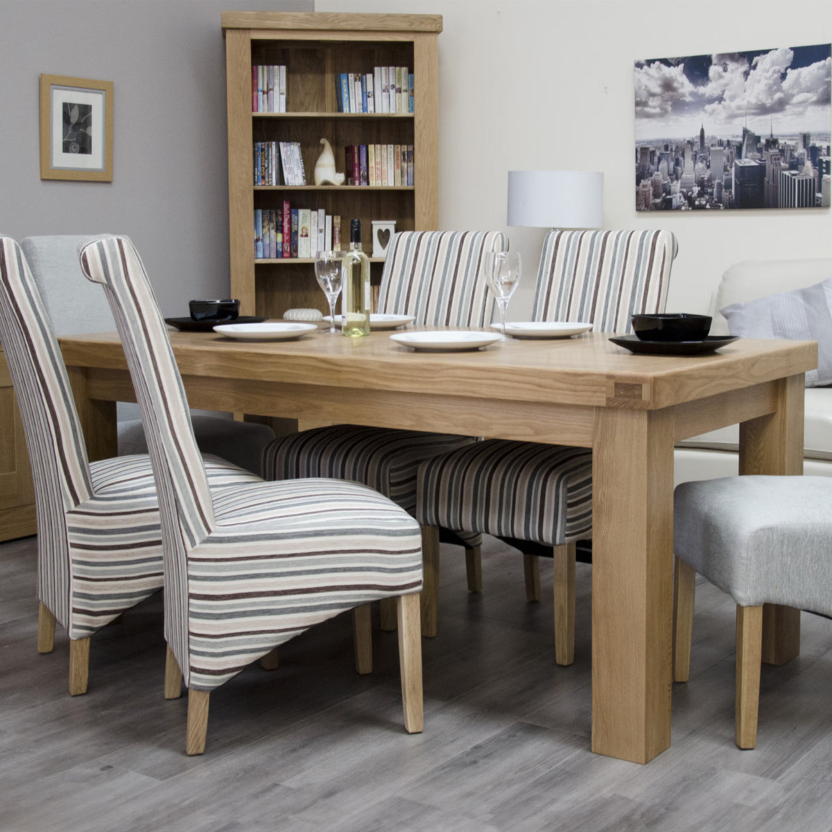 Oak dining table with striped upholstered chairs in a modern living room setup