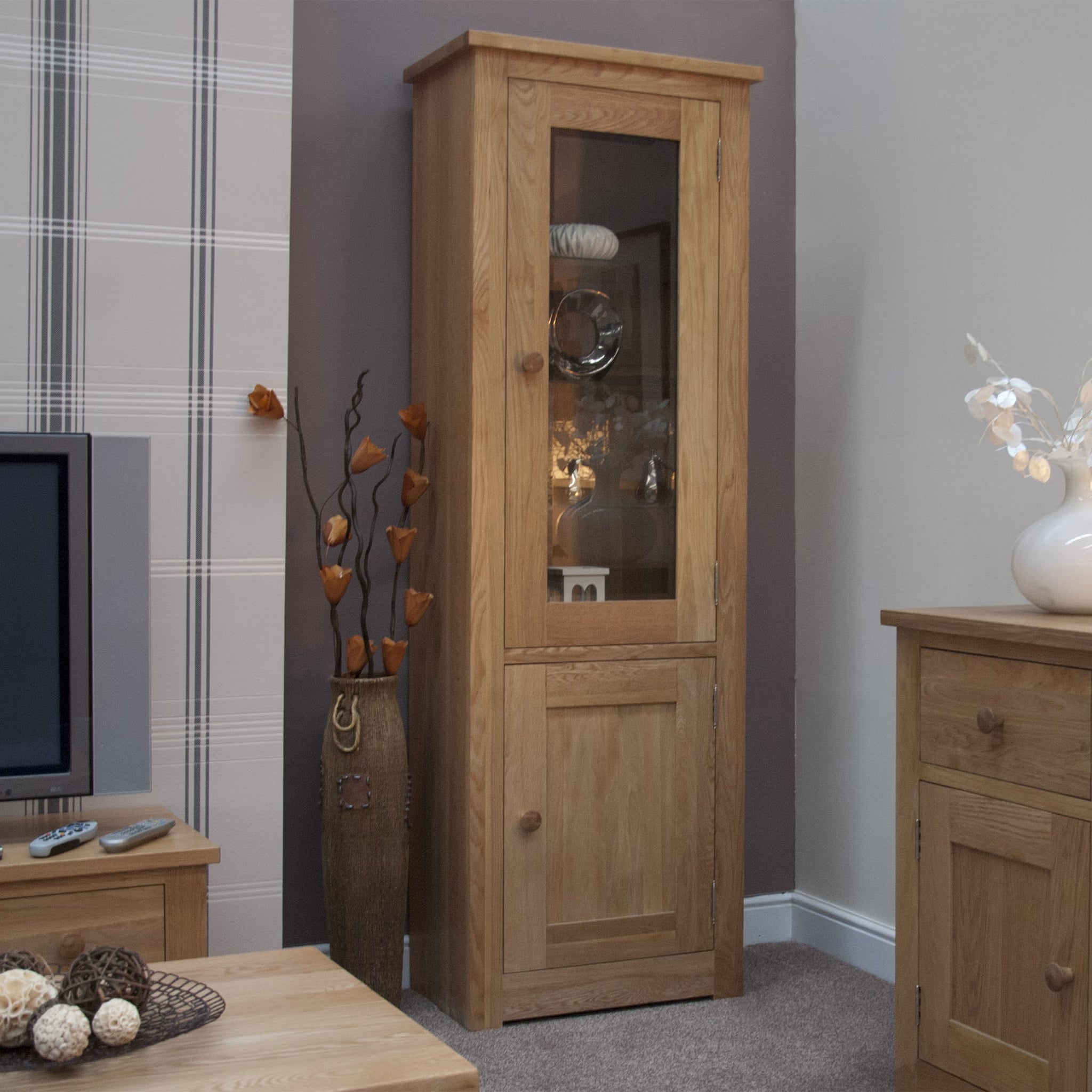 Oak display cabinet with glass door and shelving in living room corner