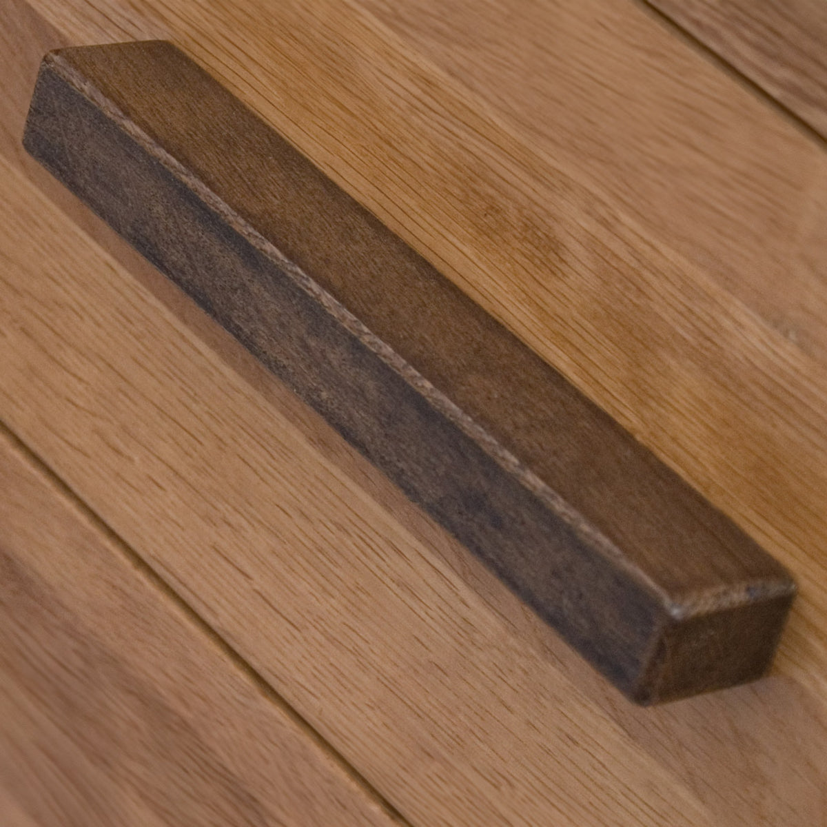 Close up of wooden drawer handle on light oak furniture