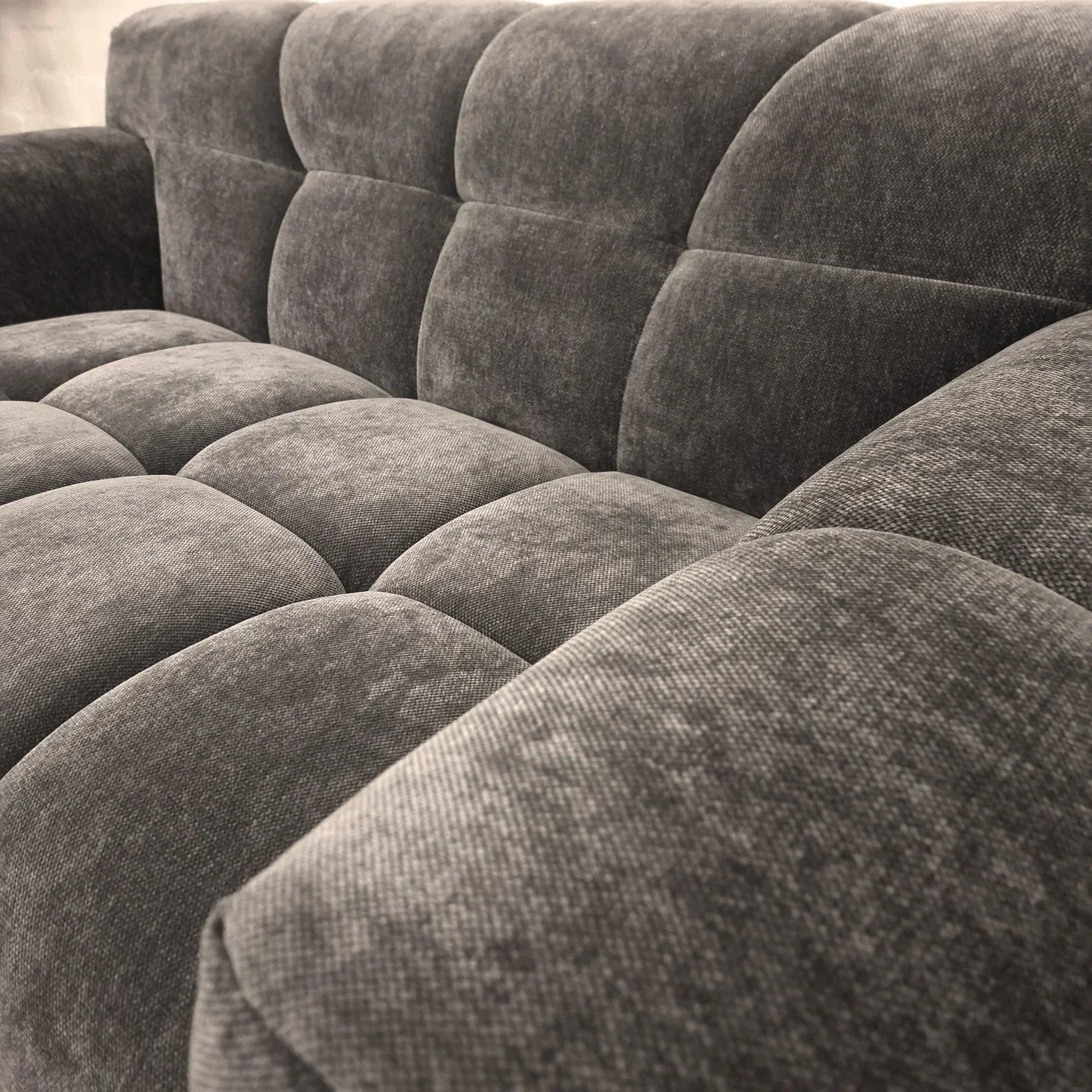 Grey fabric sofa with tufted seat and backrest, close-up of upholstery texture