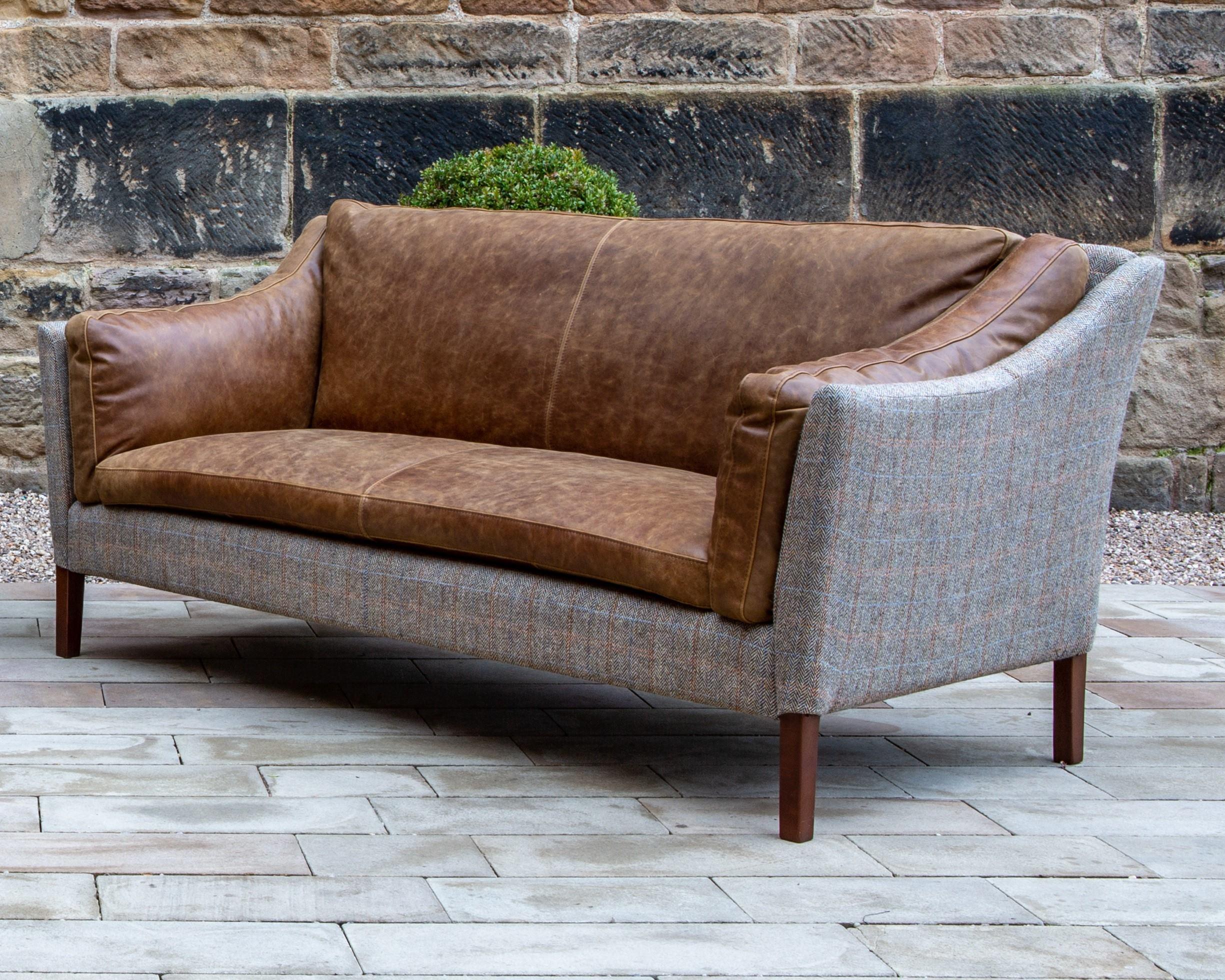 Brown leather and grey fabric sofa with wooden legs on outdoor patio