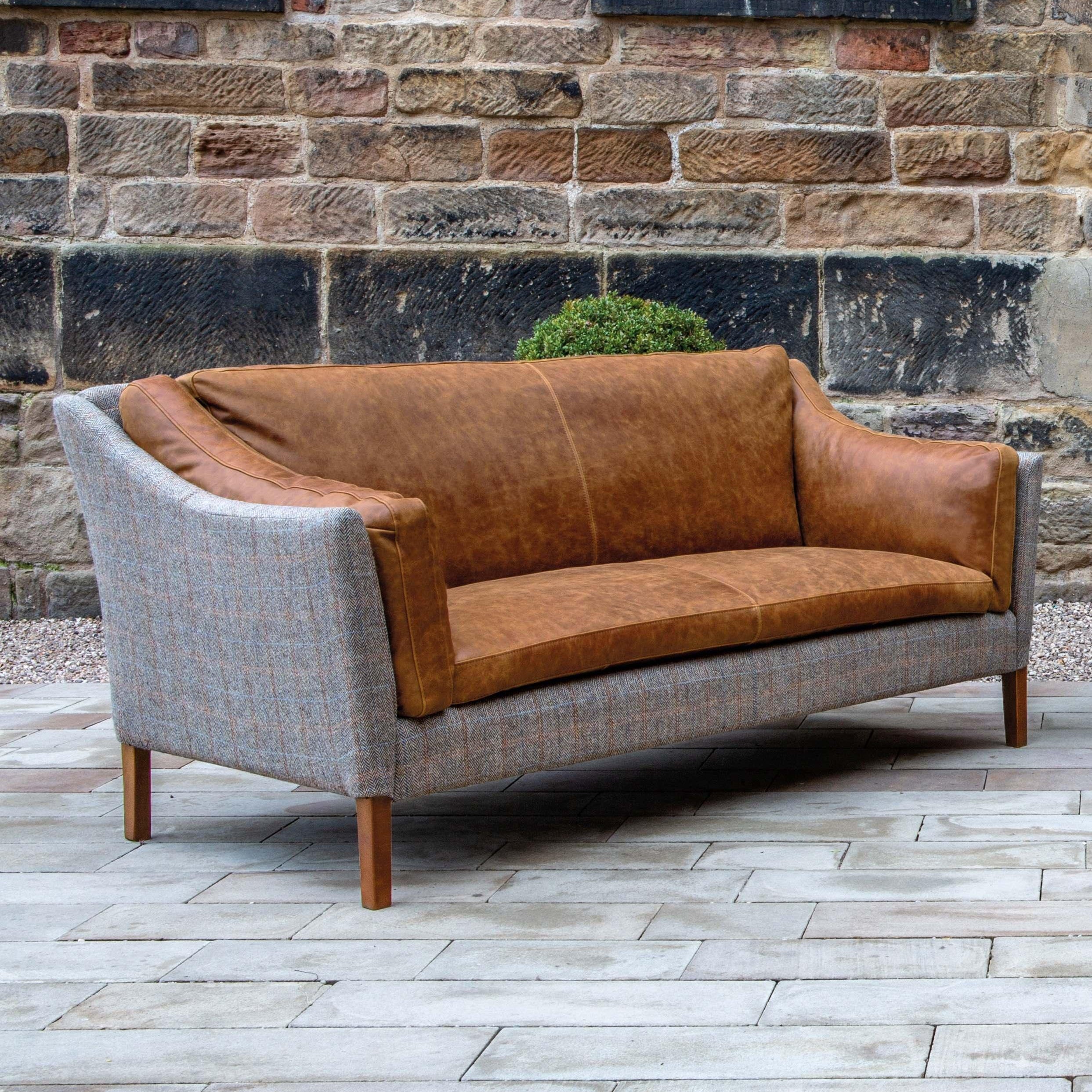Brown leather and grey fabric sofa with wooden legs on patio