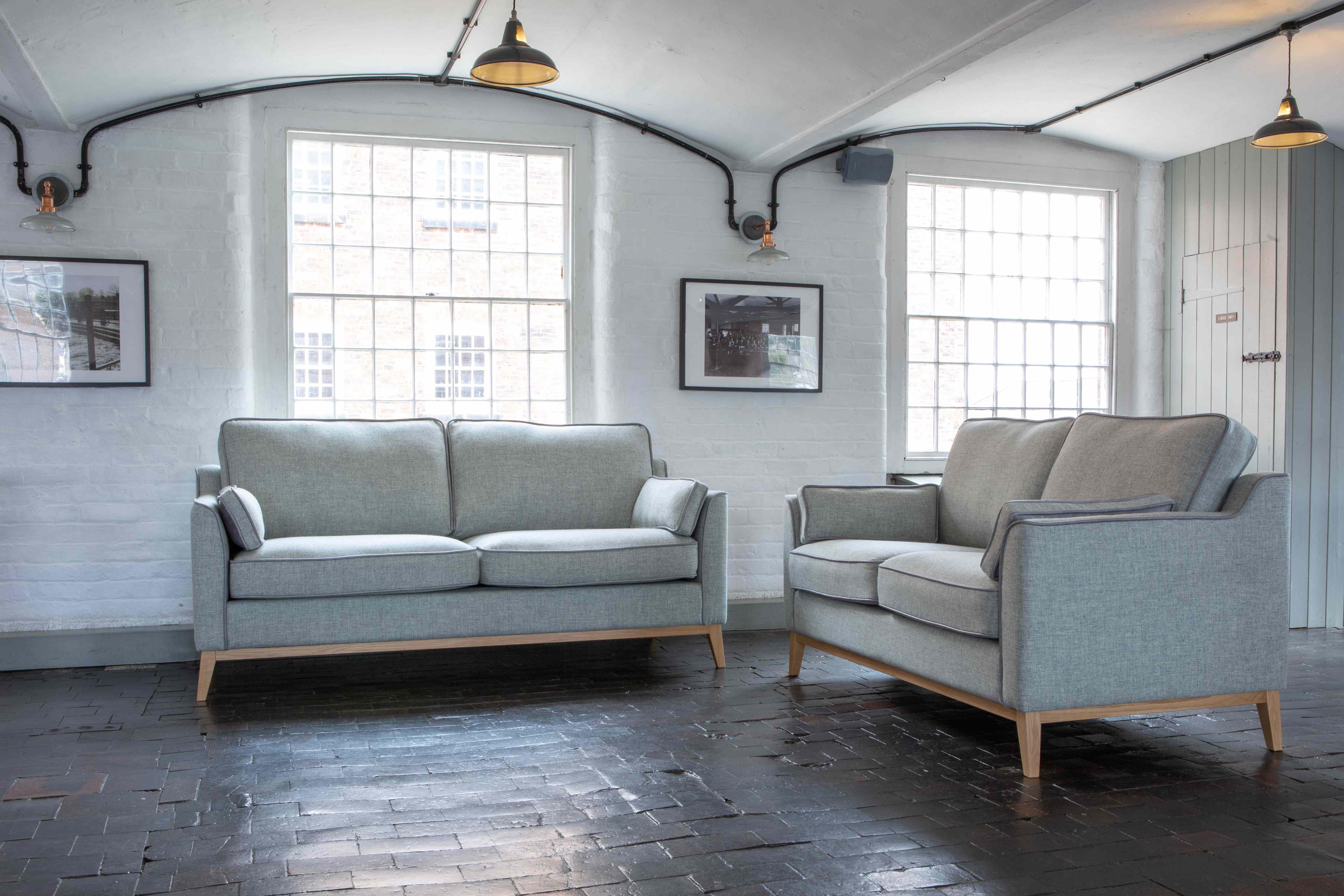 Light grey fabric sofas with wooden legs in a bright living room with large windows