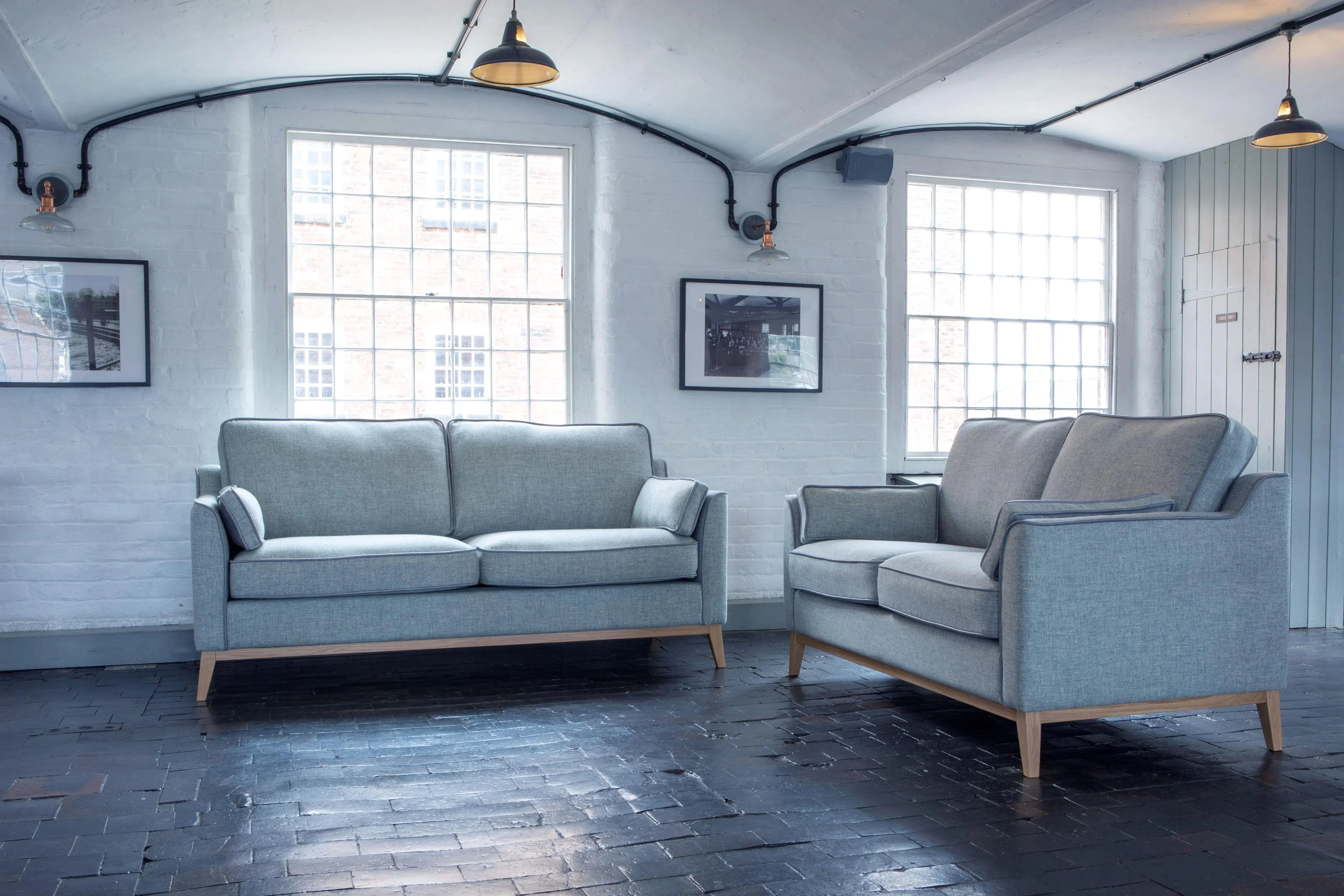 Light grey fabric sofas with wooden legs in a modern living room with large windows