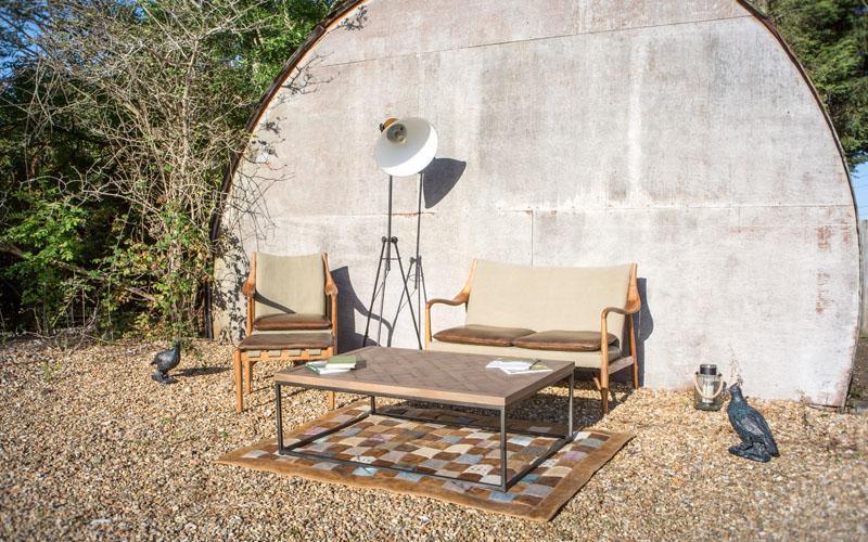 Outdoor wooden garden furniture set with beige cushions and coffee table on pebble patio