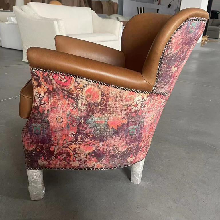 Brown leather armchair with floral patterned fabric back and nailhead trim, side view