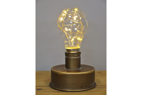 Metallic industrial-style table lamp with a round base and a light bulb filled with warm fairy lights, front view.