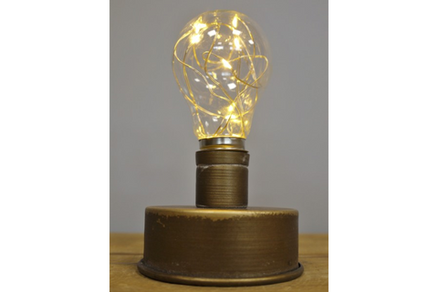 Small industrial-style table light with cylindrical bronze metal base and clear glass bulb with warm LED string lights