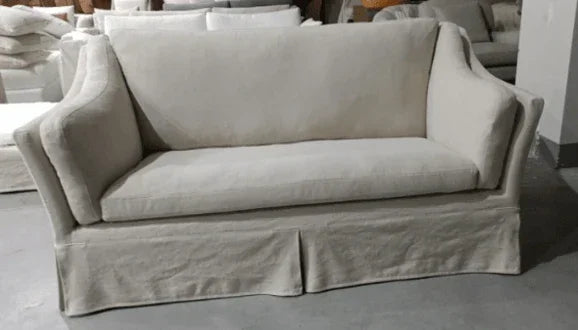 Neutral fabric sofa with cushioned back and arms, straight skirt, placed in showroom setting