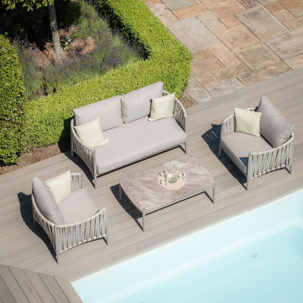 Grey outdoor sofa set with cushioned chairs and coffee table on poolside decking