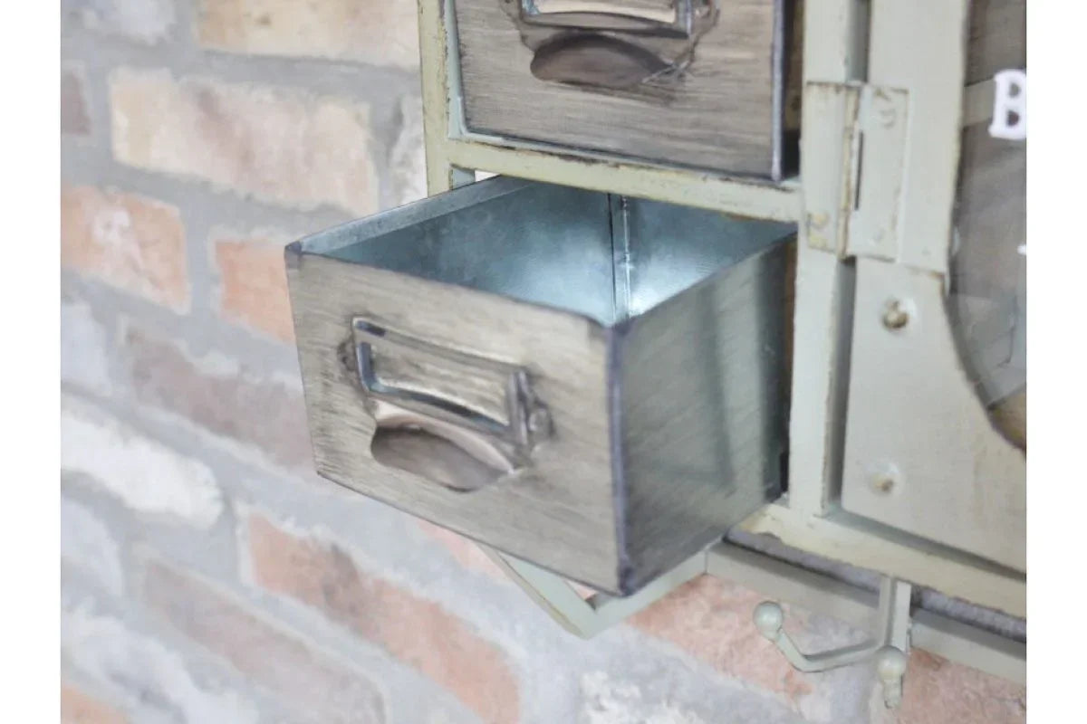 Rustic metal storage drawer unit with open pull-out drawer against brick wall