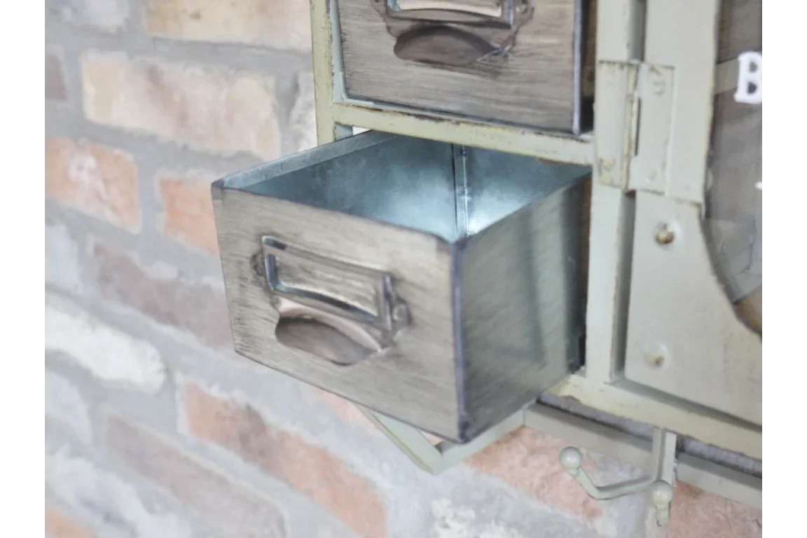 Industrial metal storage drawer with label holder, partially open against brick wall