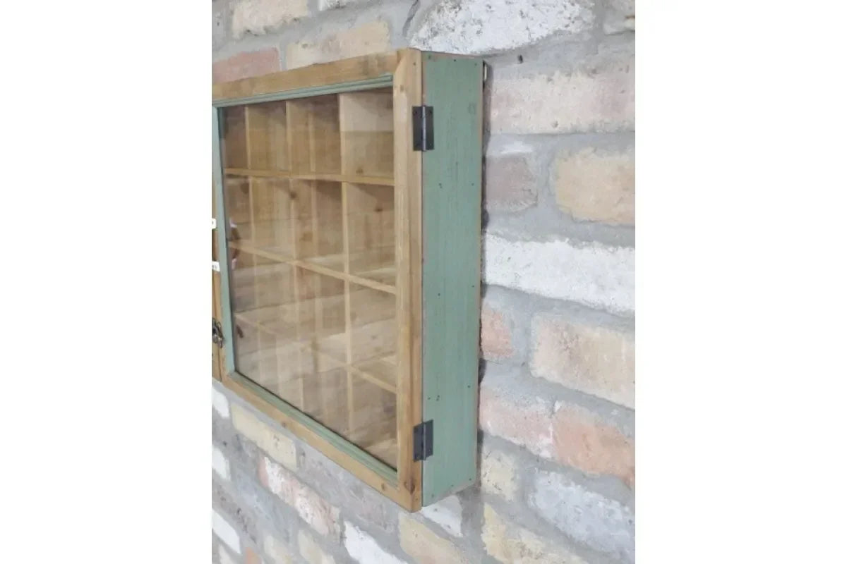Wall mounted wooden display cabinet with glass door and green frame against brick wall