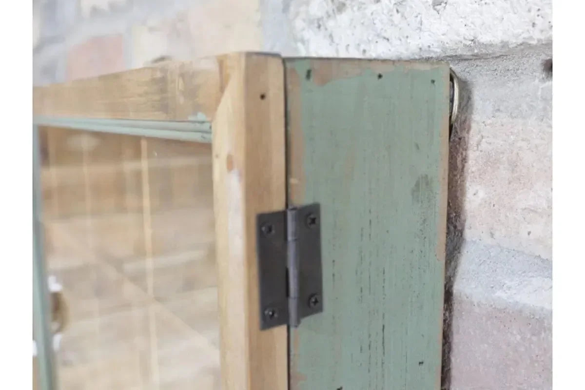Close-up of wooden display cabinet hinge with glass door and green painted frame