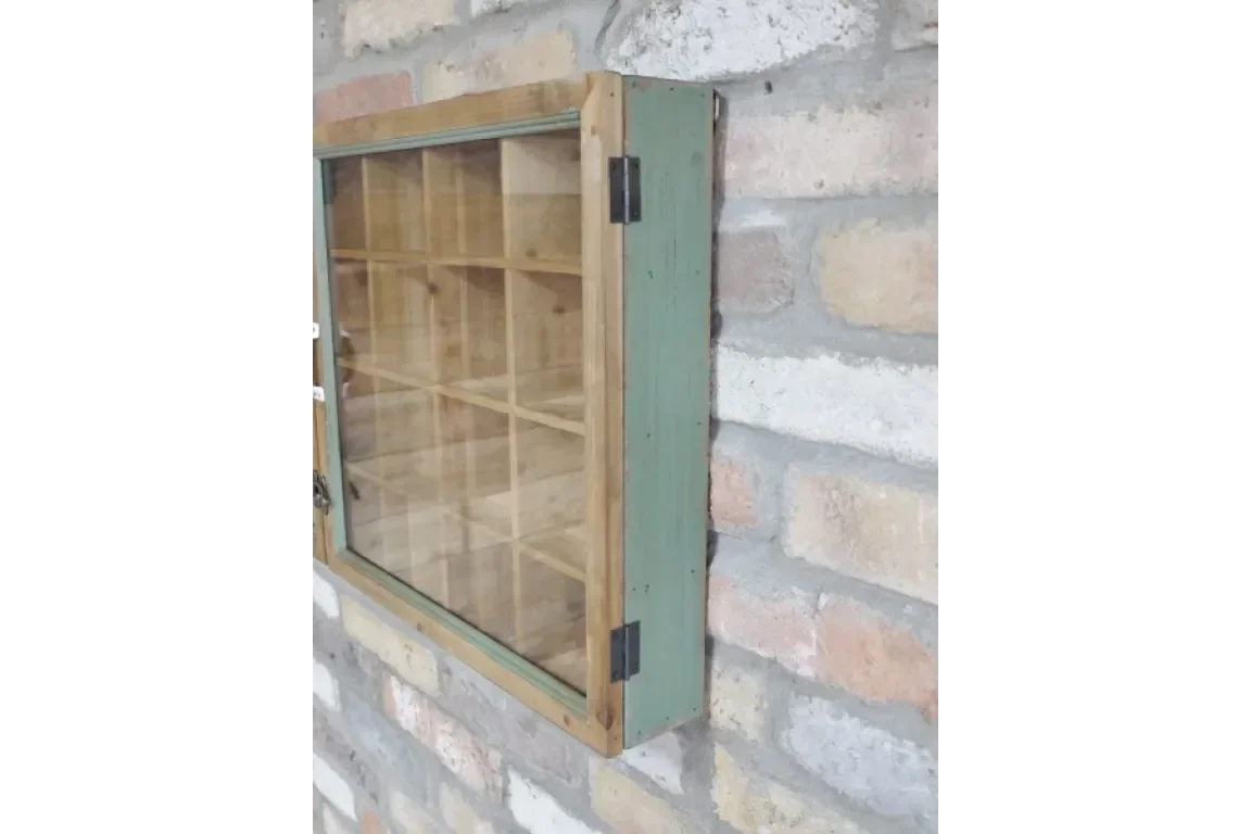 Wooden display cabinet with glass door and multiple compartments mounted on brick wall