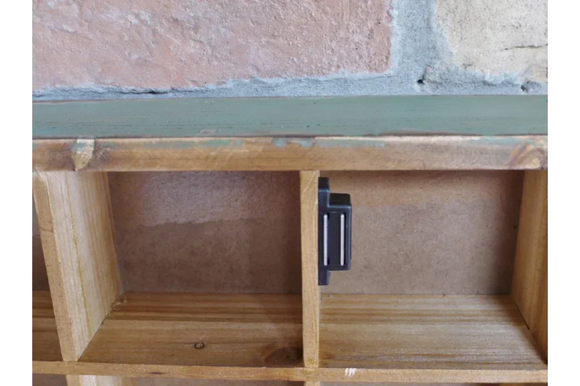 Wooden shelving unit with green top edge and metal magnetic latch inside compartment