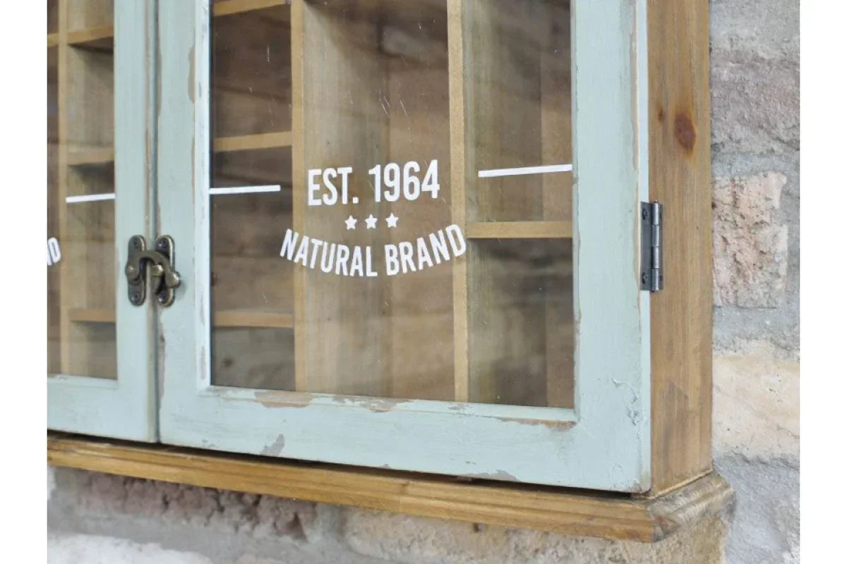 Rustic wooden display cabinet with glass doors and metal latch against a stone wall