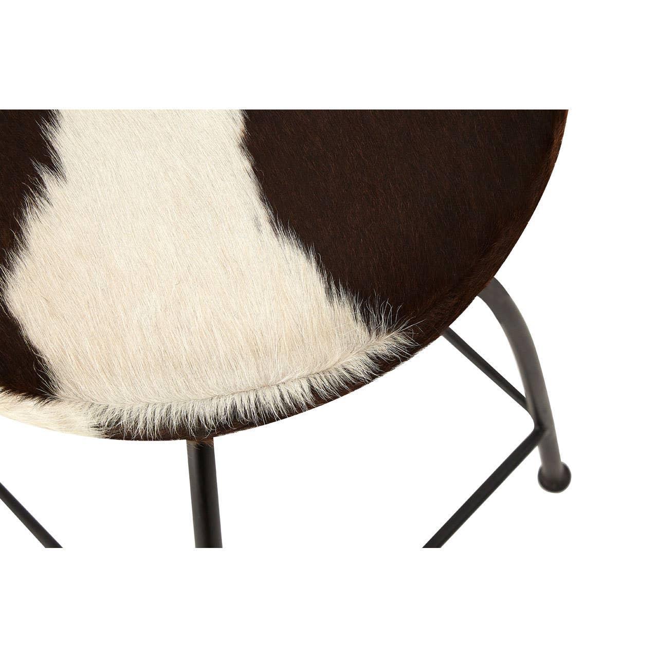Cowhide stool seat with black and white pattern and metal frame, close-up angle