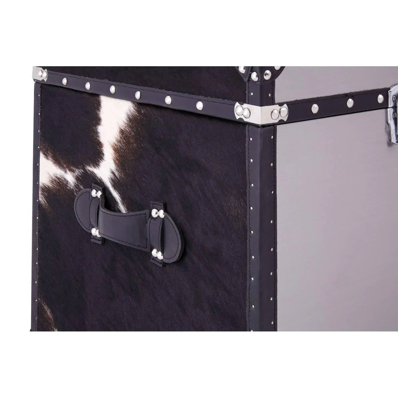 Black and white cowhide storage trunk with studded trim and leather handle close-up