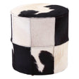 Round stool featuring a patchwork design of black and white hair-on leather, showcasing a mix of solid and patterned sections. The stool has a smooth top and a sturdy base, suitable for use as extra seating or a decorative accent in home decor