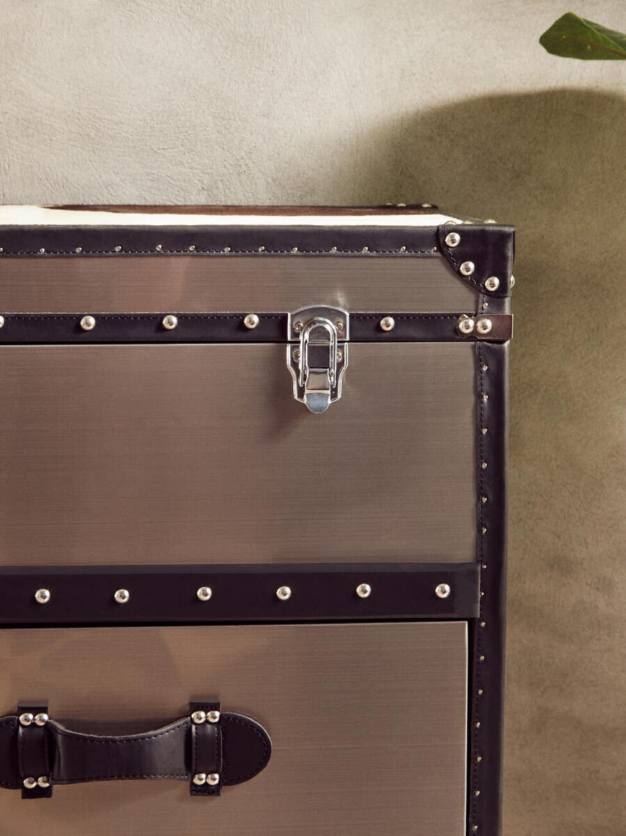 Black and white hair-on leather cabinet featuring three drawers, adorned with decorative metal studs and a sturdy handle. The cabinet has a sleek, modern design with a latch closure, set against a neutral background