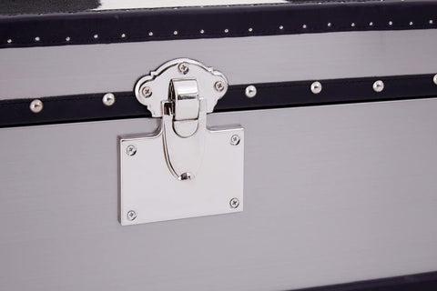 A close-up view of a black and white hair-on-leather cabinet featuring three drawers. The cabinet has a sleek design with a metal latch and a decorative white plate. The texture of the hair-on-leather is visible, showcasing a mix of black and white patterns