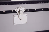 A close-up view of a black and white hair-on-leather cabinet featuring three drawers. The cabinet has a sleek design with a metal latch and a decorative white plate. The texture of the hair-on-leather is visible, showcasing a mix of black and white patterns