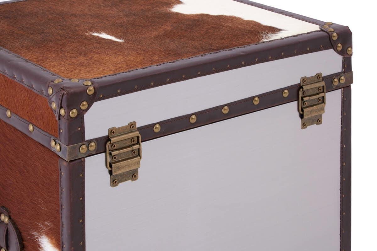 Brown and white hide storage trunk with metal stud details and brass latch corners