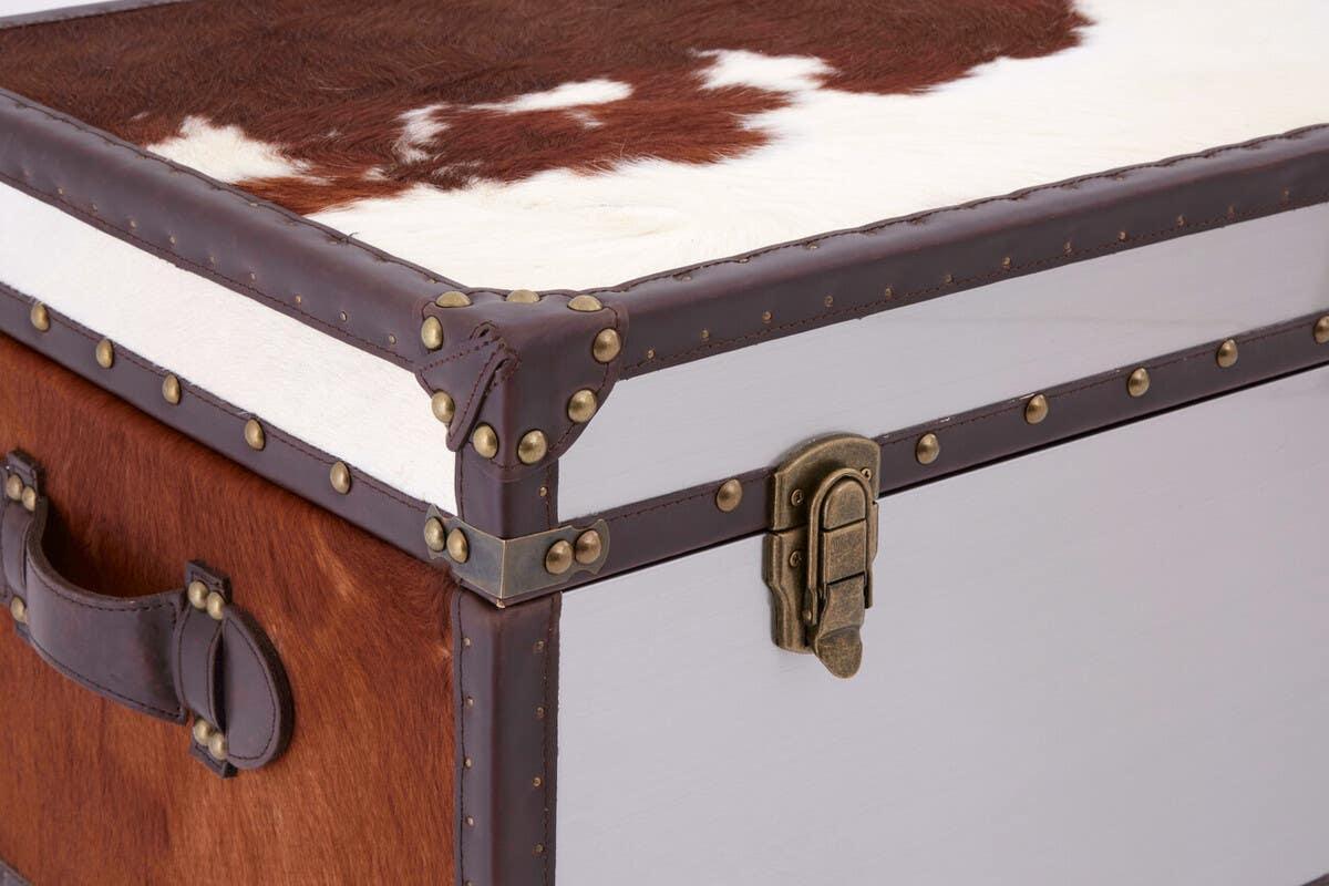 Brown and white cowhide storage trunk with leather trim and brass stud details