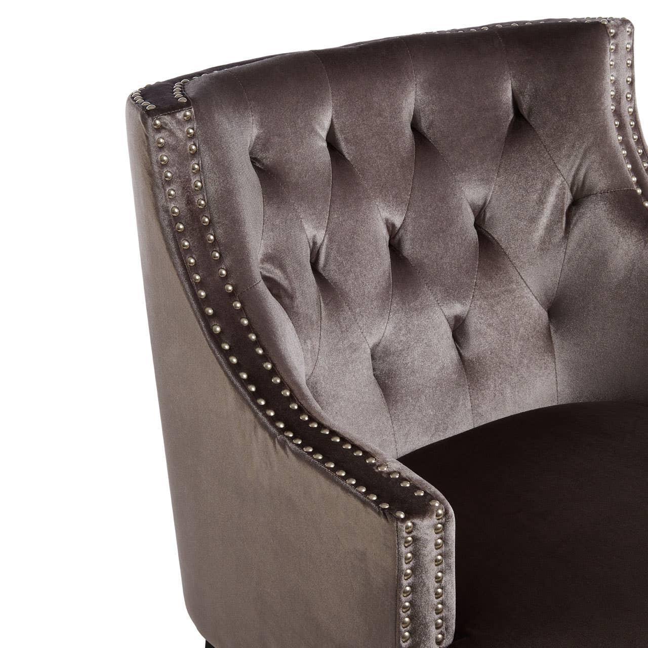 Tufted velvet accent chair with nailhead trim and curved backrest, close-up view