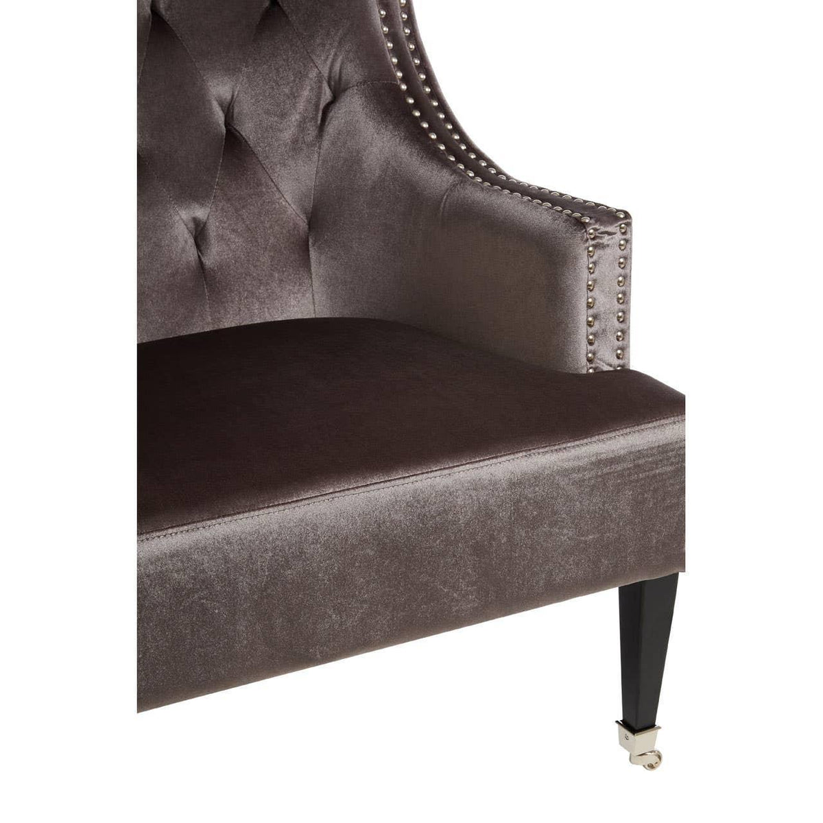 Velvet armchair with button-tufted back, studded trim, and black wooden leg on castor