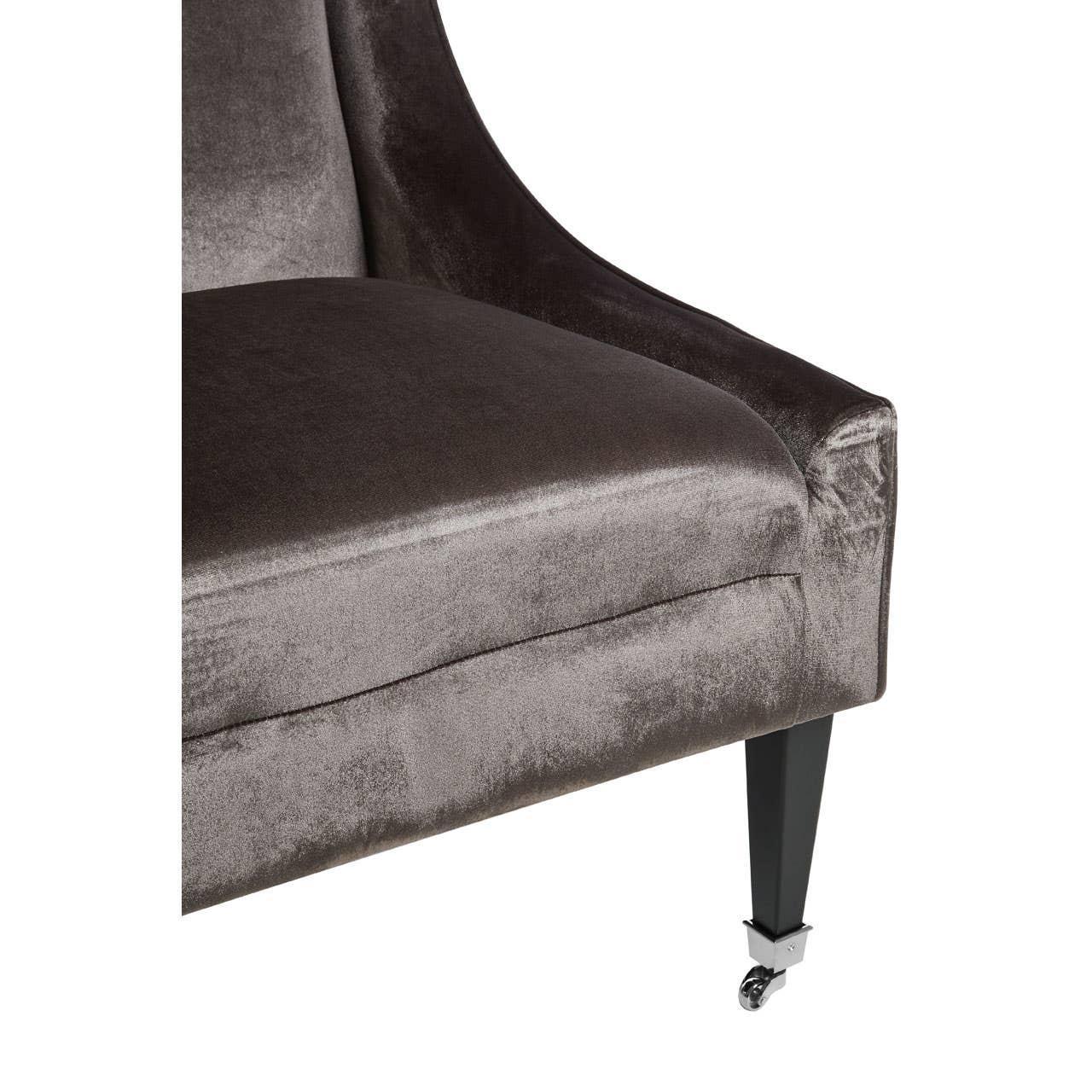 Grey velvet armchair seat and sleek black leg with chrome caster detail