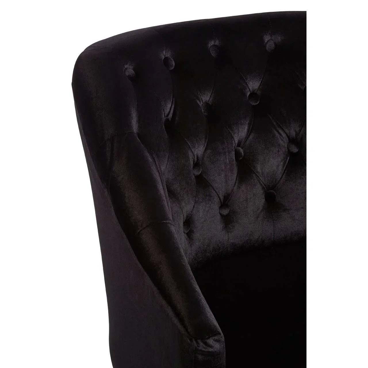 Black velvet armchair with button-tufted backrest, close-up of curved arm and fabric texture