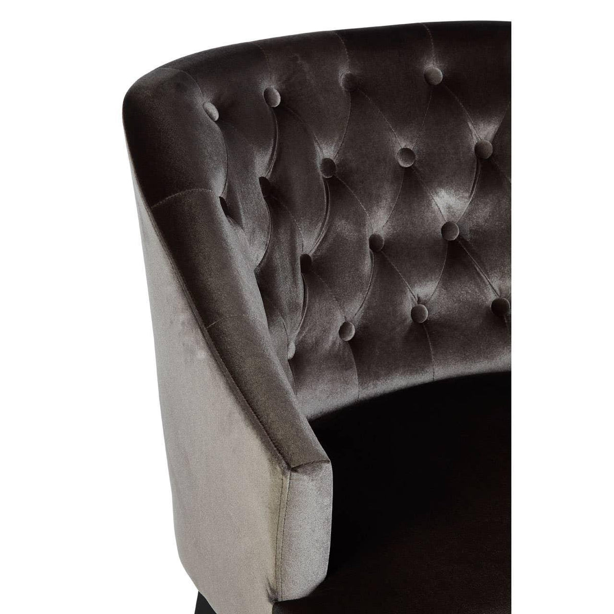 Grey velvet armchair with curved tufted backrest and padded seat, close-up side view