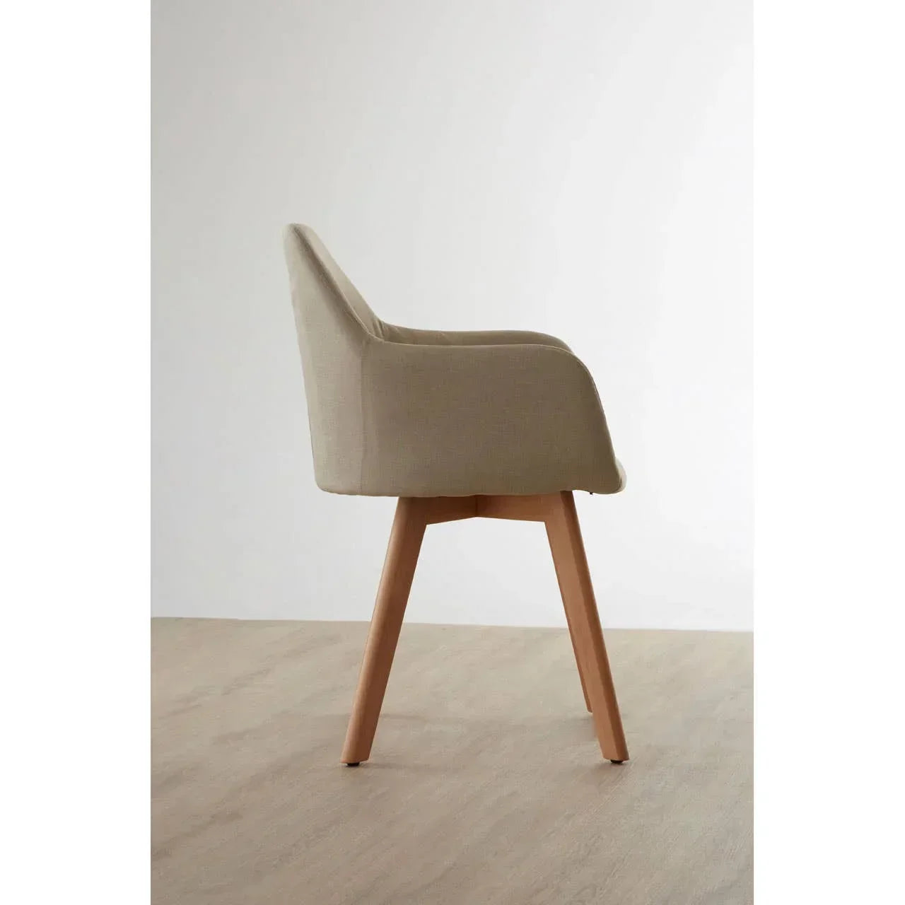 Beige fabric dining chair with wooden legs in side profile on light wood floor