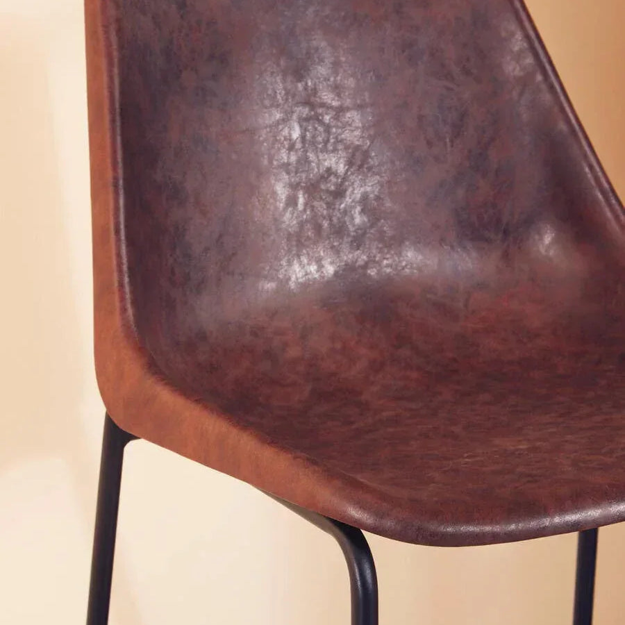 Brown faux leather bar stool with black metal legs against beige background