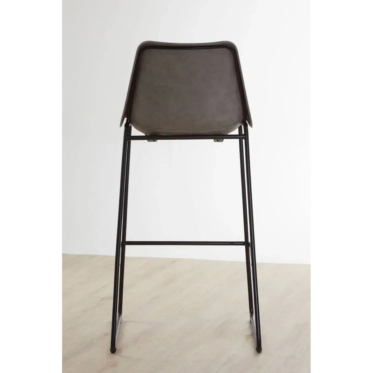 Grey bar stool with black metal legs shown from the back on light wood floor