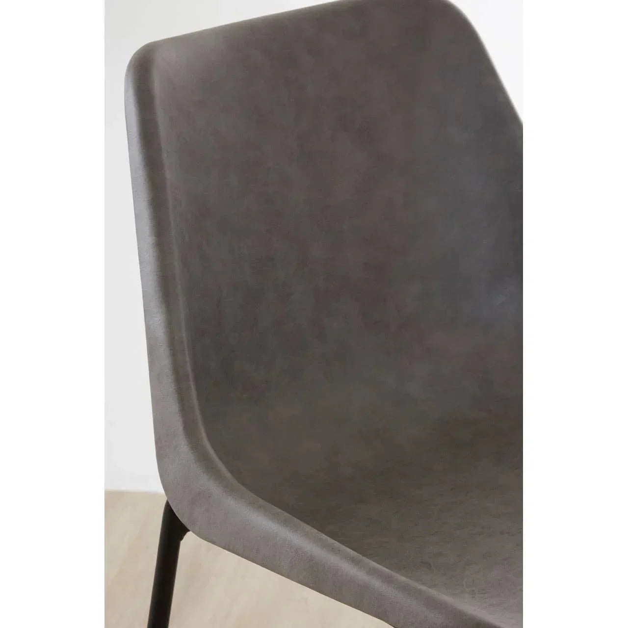 Close-up of grey faux leather dining chair seat with black metal legs