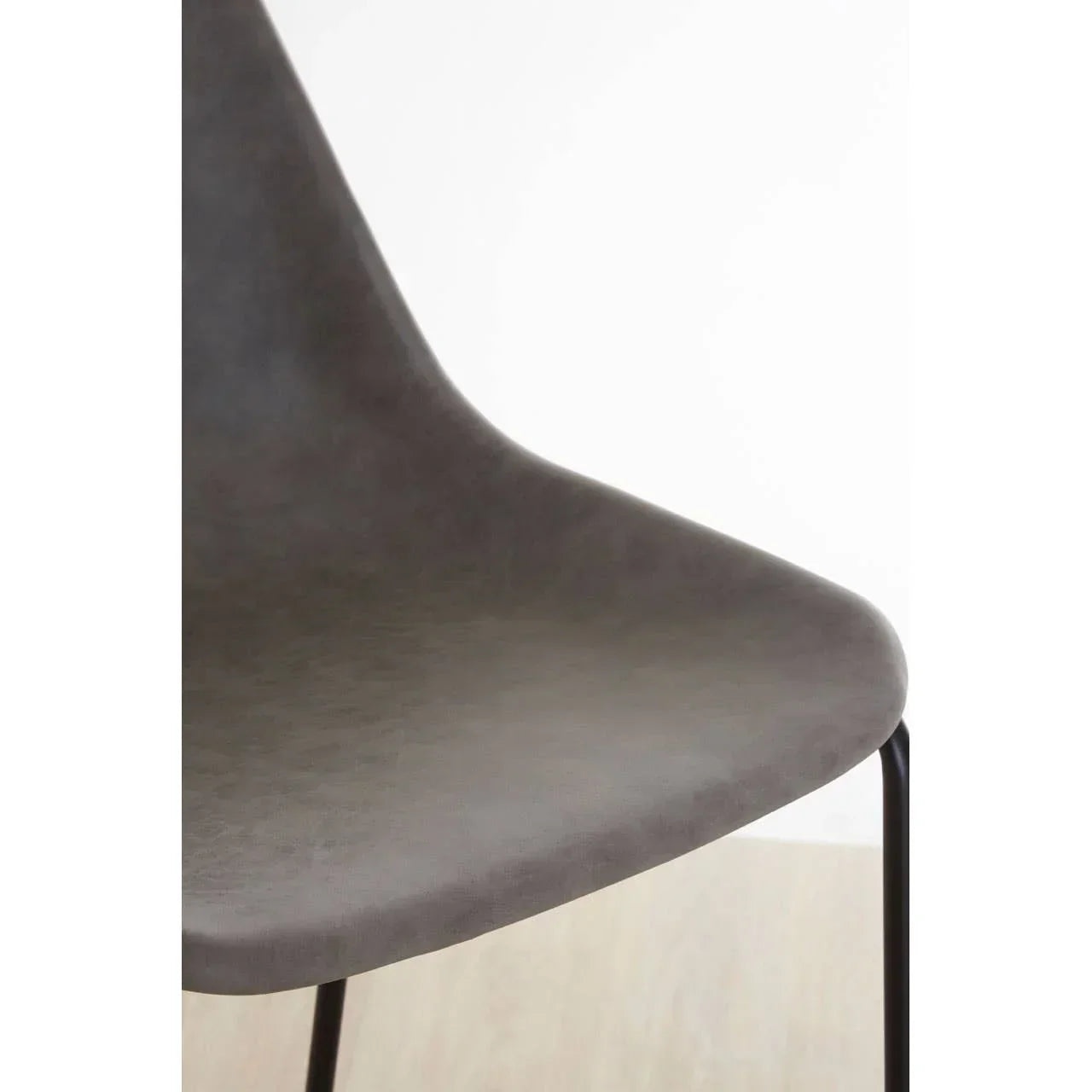 Close up of modern grey dining chair seat with black metal legs on wooden floor