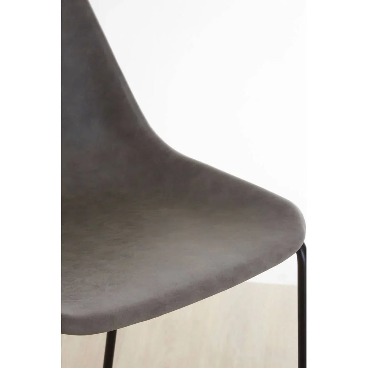 Close up of modern grey dining chair seat with black metal legs on wooden floor