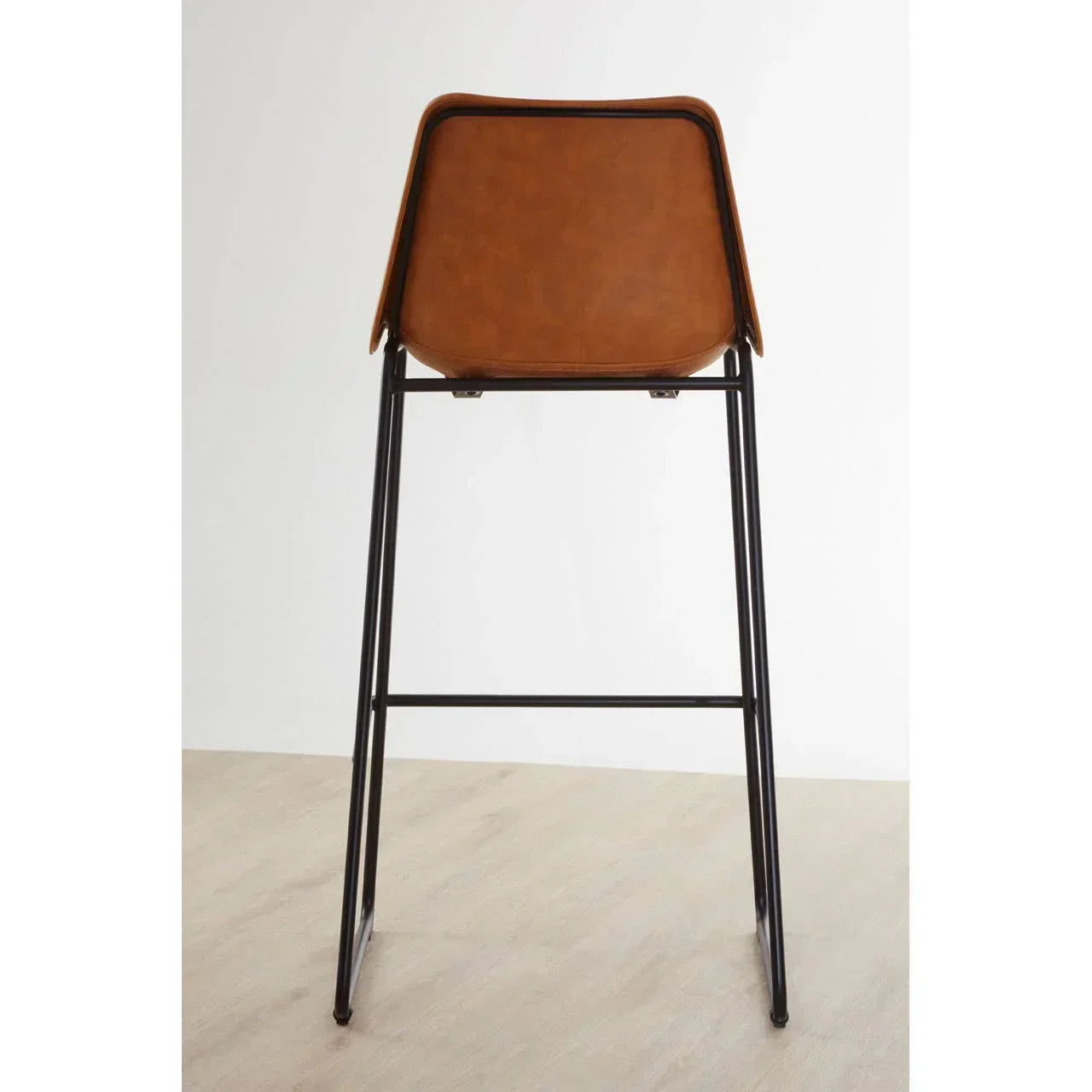 Brown leather bar stool with black metal legs, rear view on wooden floor