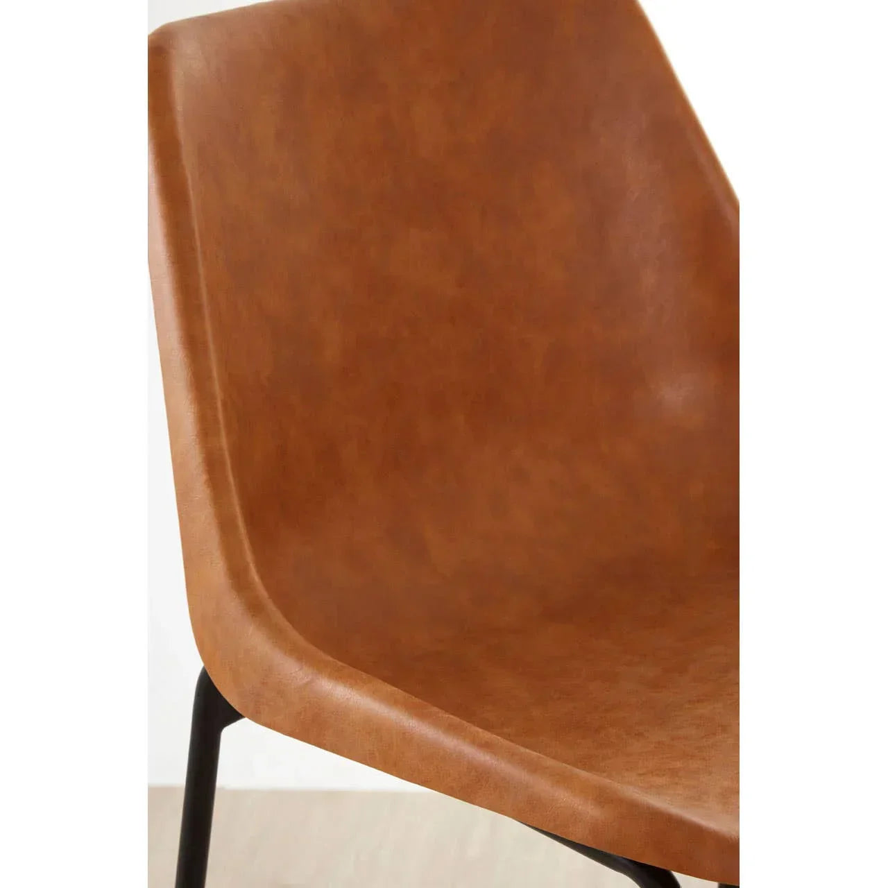 Close up of brown faux leather dining chair seat with black metal leg
