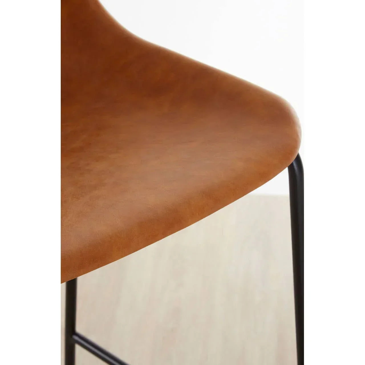 Closeup of brown faux leather dining chair seat with black metal legs