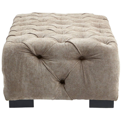 Rectangular footstool upholstered in natural fabric with a tufted design, featuring a soft, textured surface and four dark wooden legs. The footstool has a neutral beige color that complements various decor styles