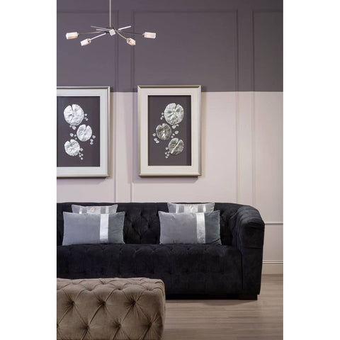 Rectangular footstool upholstered in natural fabric with tufted detailing, placed in a modern living room setting featuring a dark sofa and framed floral artwork on the wall. A contemporary light fixture hangs above, adding a stylish touch to the decor