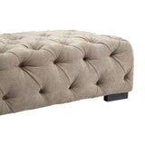 Rectangular footstool upholstered in natural fabric with a tufted design, featuring a soft beige color and a low-profile black base