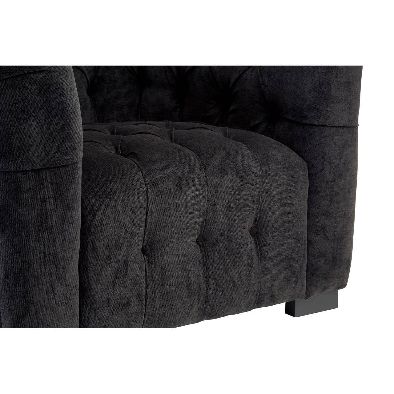 Close-up of black velvet tufted sofa arm and seat cushion