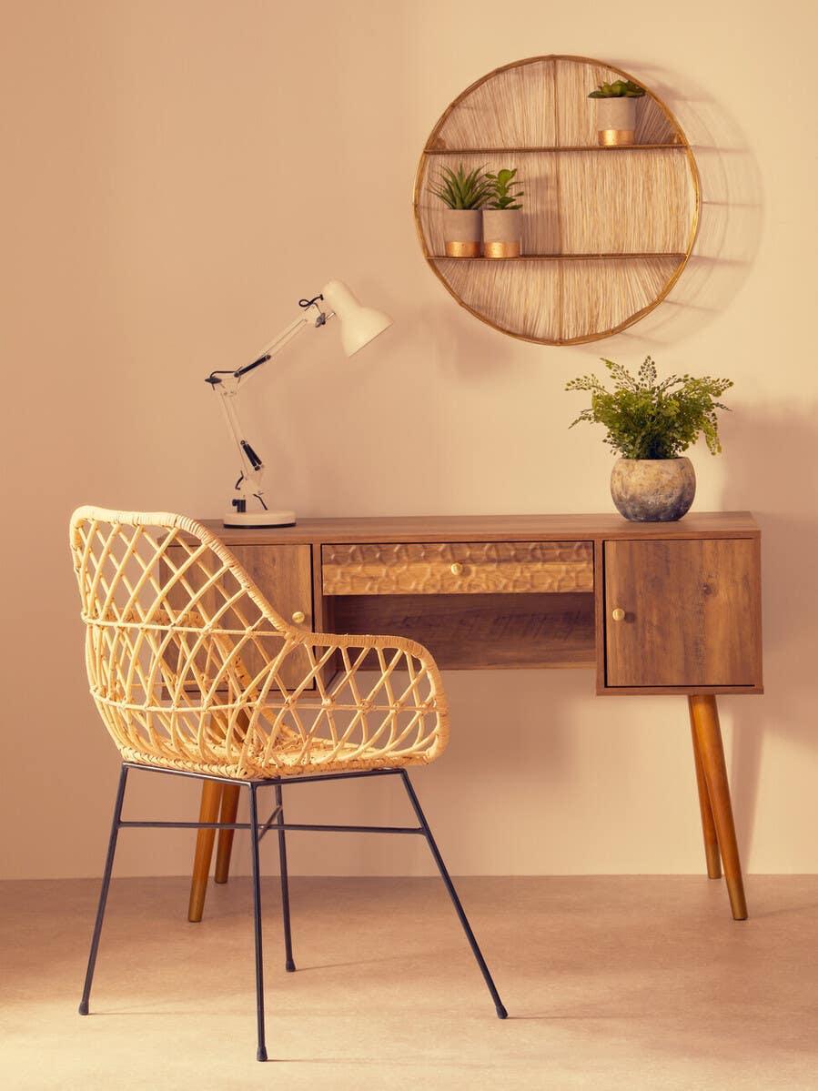Wooden desk with rattan chair, white lamp and wall shelf with potted plants in home office
