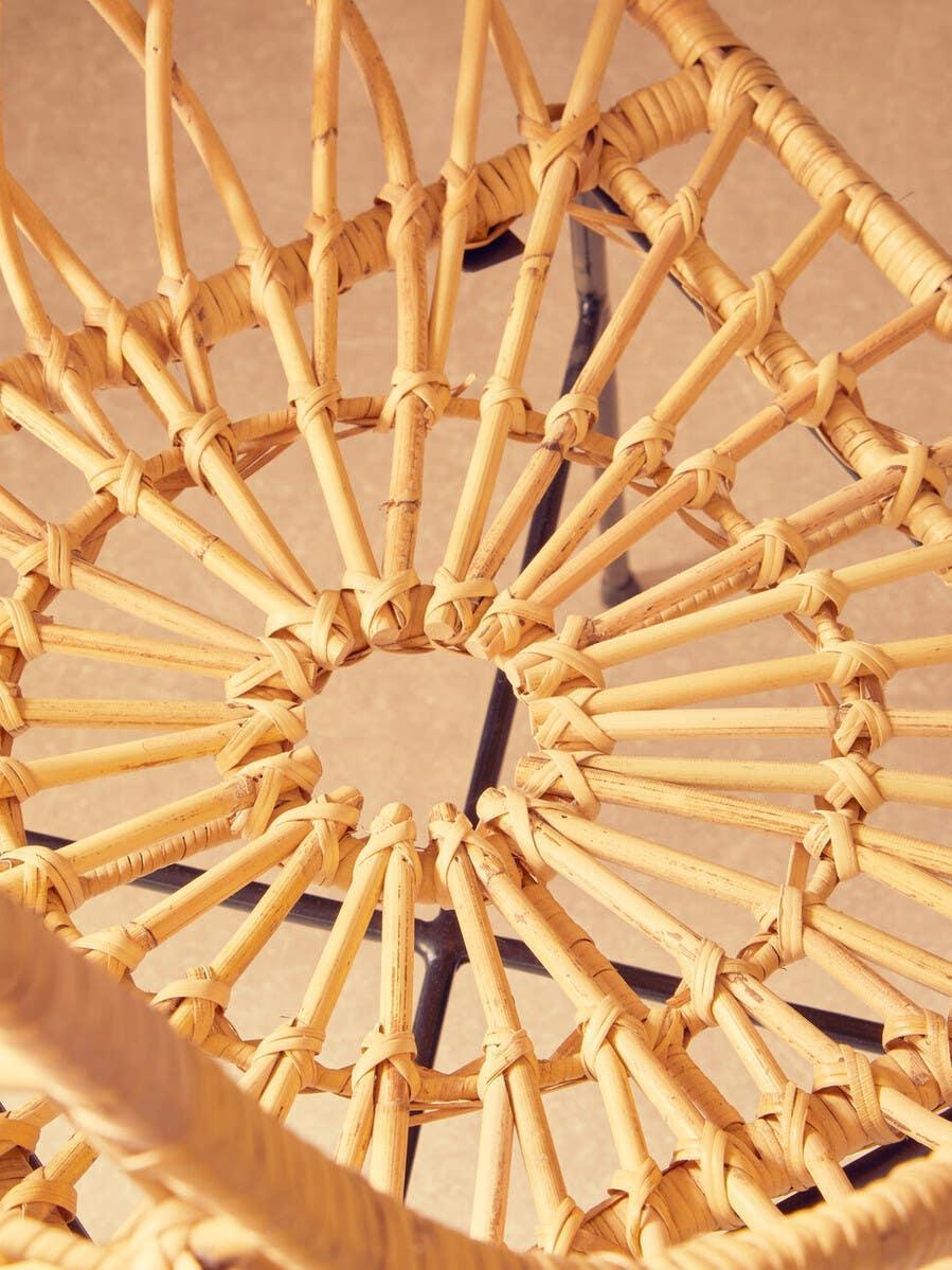 Close detail of woven rattan chair seat with circular pattern and metal frame support